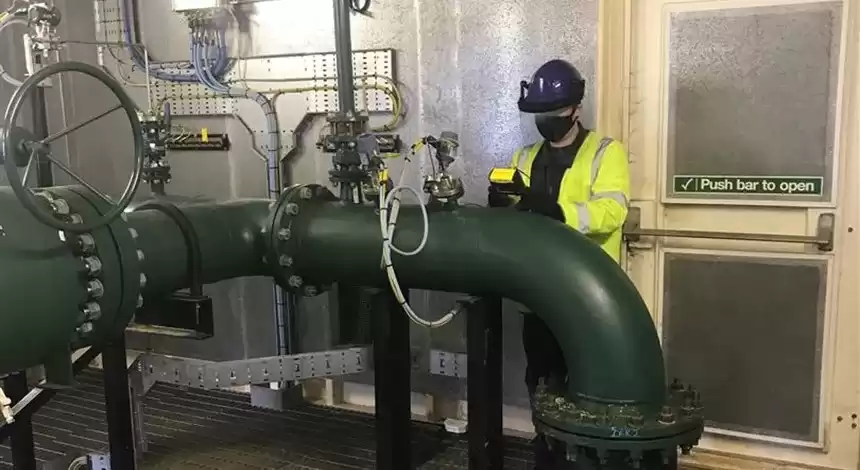 A person wearing safety equipment performing maintenance on a gas pipeline.