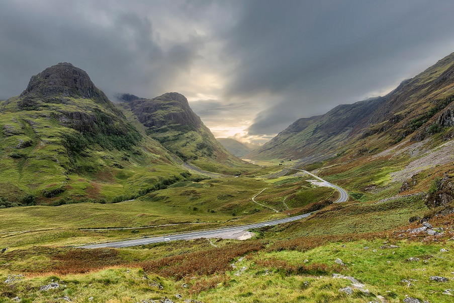 A road in Scotland in between grass covered hills.