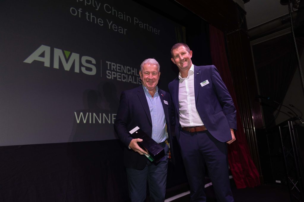 Two people in business dress posing for a photo with an award at Murphy's annual Supplier Awards.