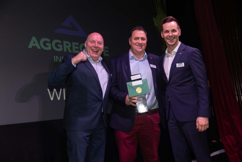 Three people in business dress holding an award at Murphy's annual Supplier Awards.