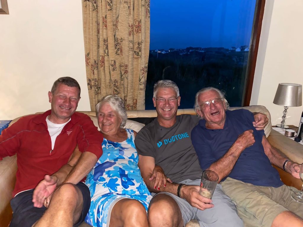 Four people sat on a sofa smiling and laughing.