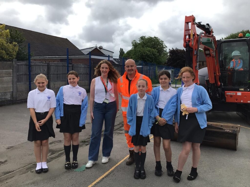 Two Murphy employees with children in school uniform stood in front of an excavator.