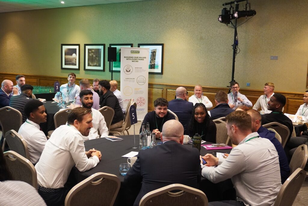 A group of people sat at a circular table having a discussion.
