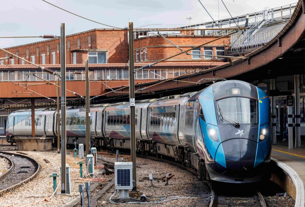 An blue and silver train at a train station in the day time. 
