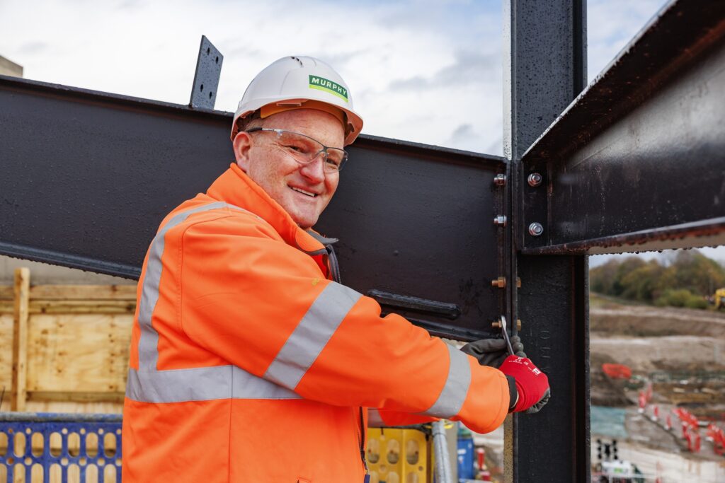 A person wearing Murphy-branded uniform tightening a bolt on a metal frame.
