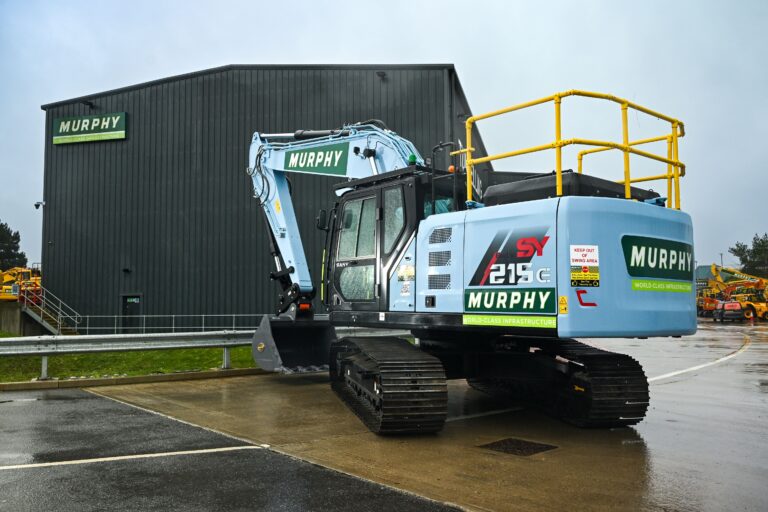 A new Murphy-branded electric excavator in front of a black building with the Murphy logo.