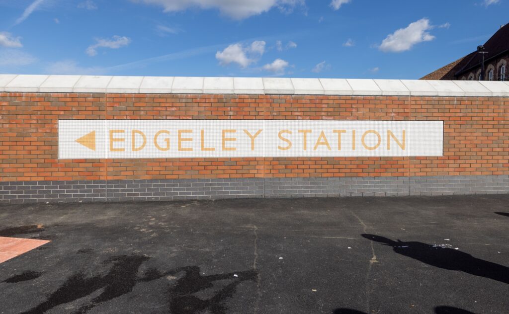 A brick wall with a mosaic on it that reads "Edgeley Station." 
