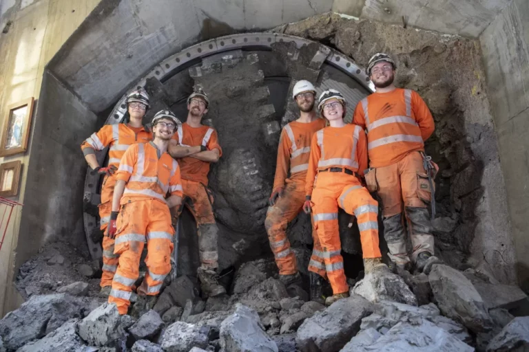 A group of workers in Murphy branded uniform and safety helmets standing in a tunnel in front of some machinery.